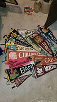 Photograph showing a collection of assorted felt pennants with Canadian place names like Halifax, Chilliwack B.C., Cape Breton, and Montreal with graphics and text.