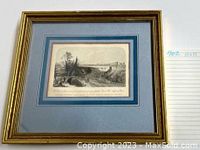 Framed monochrome landscape print in a gold frame with blue double matting.