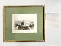 Framed artwork showing landscape scene with trees and rooftops, green mat, silver-toned frame