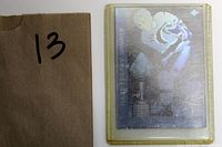Photo of the card taken with a brown envelope marked with the number 13, showing the card's backside and protective case