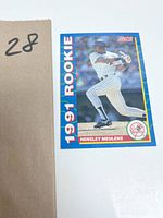 Front view of a 1991 Score rookie Hensley Meulens baseball card showing him swinging the bat in a pinstripe New York Yankees uniform with blue border vertical '1991 Rookie' text.