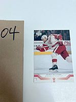 Hockey sports card featuring Steve Yzerman shooting a hockey puck in Detroit Red Wings uniform.
