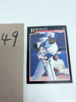 First photo shows a 1991 Score baseball card of Rob Ducey, outfielder for the Blue Jays, with a beige background and a number 49 card marker.