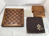Wooden 12x12 chessboard with two labeled wooden storage boxes containing chess pieces and one Cavalier magnetic chess set box with 5 pieces.