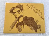 Yellow portfolio folder with a caricature drawing of a man with glasses and a cigar, and handwritten text 'A David Levine Portfolio Drawings from The New York Review of Books'.
