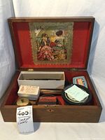 Open wooden box showing interior contents and decorative print in lid