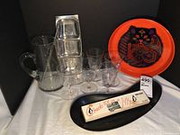 Photo showing entire lot with glass pitcher, cocktail glasses, metal snack tray, black plastic tray, metal bar tray with black cat design, and Tap-Icer box.