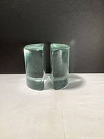 Front view of the pair of heavy glass bookends standing side by side showing rounded shape and thickness.
