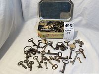Open tin on white background with keys both inside and spread outside on surface