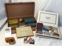 Overview photo of vintage tobacciana including tins, lighters in box, Chesterfield cigar box, matchbooks, and carved pipe head