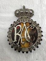 Front view of the vintage metal car club emblem showing overall design with crown, letters RAC, and Spanish flag colors with wear.
