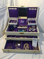 Full open jewelry box showing multiple compartments filled with jewelry