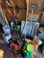 Wide shot showing multiple gardening tools including hedge trimmers, chainsaw, rakes, and snow shovels.