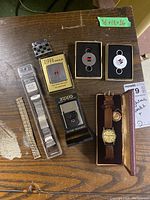 Full lot overview showing lighters, watch, bands, and key rings on wooden surface