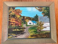 Full view of framed painting by M. Bathgate, depicting a rural fall landscape with winding road, houses and trees, signed lower left.