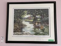 Full view of framed print depicting two people rowing a boat on a river with house and trees in background.