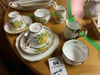 Two Royal Albert Tea Rose teacups with saucers, one side plate, and Gardenia cream and sugar set on wooden table.