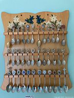 Full view of the wooden wall mount rack with 30 collector spoons arranged in three rows