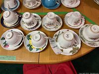 Top-down view of assorted teacups and saucers arranged upside down showing maker's marks on bases.
