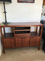Front view of wooden buffet showing top surface, lower cabinets, open shelves and drawer section.