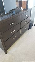 Front view of the six-drawer dresser showing its dark brown finish and silver handles.