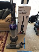 Vacuum and original box side by side on floor, showing overall lot contents