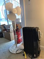 Full view of the white Honeywell floor fan beside the black portable heater.