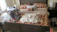 View of bed with linens, decorative pillows, and packaged bed ensemble on bed.