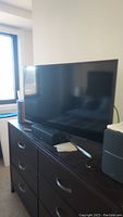 Samsung flat screen TV on dresser, remote control visible in front of TV base.