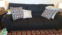 Front view of dark gray upholstered three-seat sofa with four accent pillows