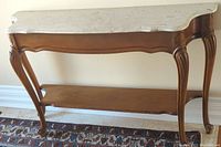 Full view of the console hall table showing wood frame, marble top, and lower shelf on patterned rug.