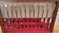 Top view of 12 dinner knives with ornate silverplate handles in red velvet-lined wooden box.