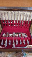 Full flatware set arranged in red velvet–lined wooden box