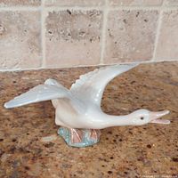 Side angle showing the duck with outstretched wings, glossy white and detailed texture.