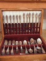 Full view of flatware inside open velvet-lined wooden box showing arrangement of knives, forks, spoons and serving utensils with Old Colony floral and diamond handles.