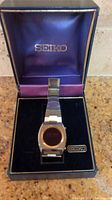 Photo of men's Seiko digital wristwatch displayed inside blue presentation box with satin lining and gold logo.