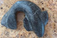 Photo showing the top view of the dark soapstone carving depicting a marine animal with curved body and fins.