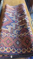 Top-down view of rolled carpet showing central geometric design and color palette.