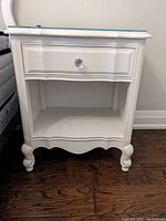 Front view showing one drawer with crystal knob and open lower compartment