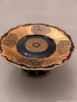 Top angle showing hand painted dark blue and gold floral decorative pattern on the cake stand