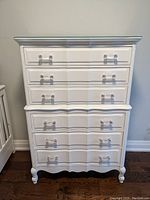 Front view of vintage white six-drawer tallboy dresser showing drawer arrangement, clear handles, and painted finish.
