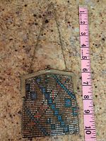 Purse laid flat with a measuring tape showing approximate 7 inch length.