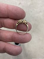Side profile view of the 10K gold ring showing the band and the three stones in prong settings.