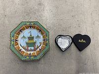 Versace octagonal bowl plate with colorful Asian pavilion design and ornate border, next to black heart-shaped Rosenthal paperweight box.