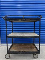 Front view of vintage Art Deco iron and marble serving trolley against blue background