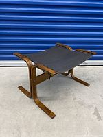 Front angled view showing entire ottoman with bentwood frame and black fabric seat.