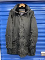 Full front view of black womens Canada Goose winter jacket size XL with zipper closed, hanging on a wooden hanger.