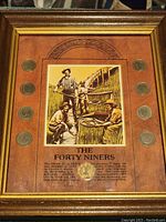 Full view of the framed coin collection with vintage gold mining illustration.