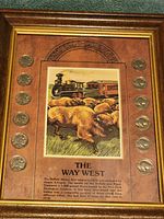 Full view of the framed Buffalo nickels with 'The Way West' central illustration, showing 12 coins spaced around a historical image of buffalo and a train.