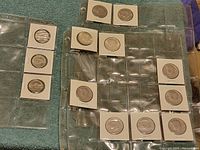 Several half dollar coins in white cardboard holders inside clear plastic sleeves, showing various designs and dates.